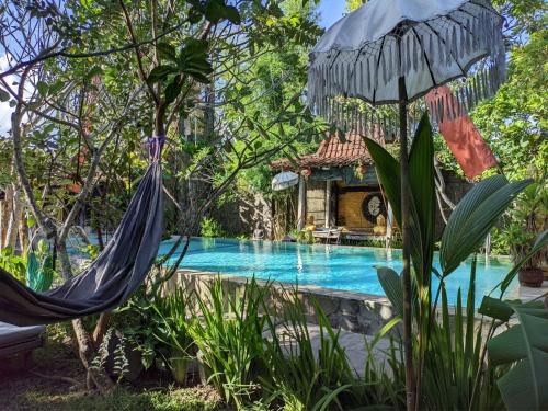 a hammock by a swimming pool in a garden at Astuti Gallery Homestay in Yogyakarta