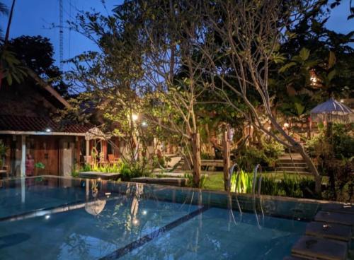 a swimming pool in a backyard at night at Astuti Gallery Homestay in Yogyakarta
