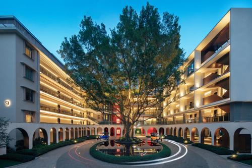 a tree in the middle of a street in front of a building at Hotel Indigo Guangzhou Haixinsha, an IHG Hotel - Social hour at Flow - Free shuttle bus to exhibition center during Canton Fair period in Guangzhou