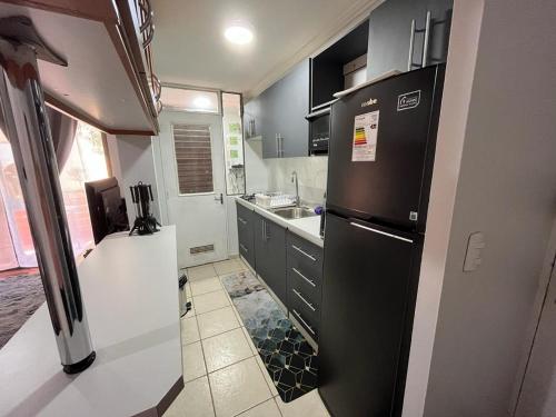 eine Küche mit einem schwarzen Kühlschrank und einer Spüle in der Unterkunft CÓMODO Y RENOVADO DEPARTAMENTO CON VISTA AL MAR in Arica