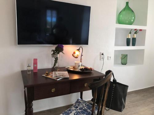 a desk with a television on a wall with a chair at Villa Vager Mani Hotel in Kalamata