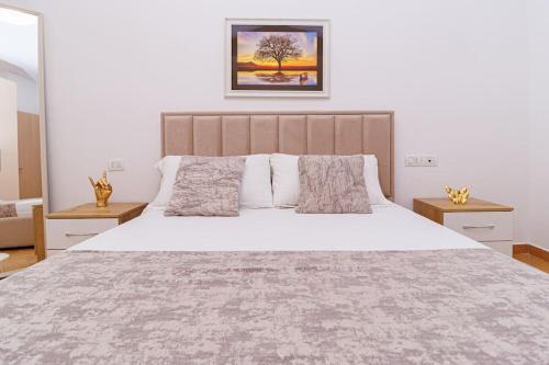 a bedroom with a large white bed with two tables at Stylish City Apartment in Vlorë