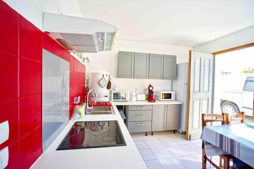 uma cozinha com armários vermelhos e brancos e um lavatório em Alaia - Maisonnette T3 à 400m plage em Bidart