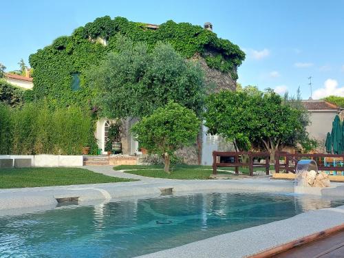 a swimming pool in front of a house with a tree at Giardini Penelope in Ciampino