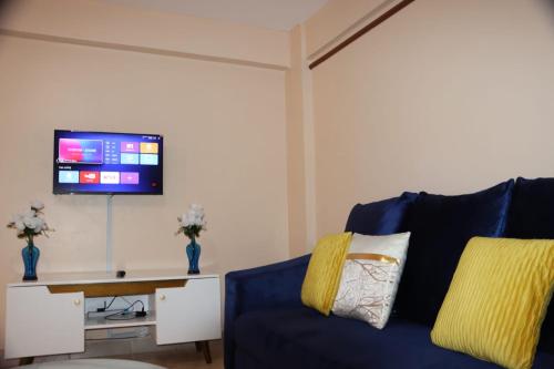 een woonkamer met een blauwe bank en een flatscreen-tv bij Jayhomes Near All embassies. in Nairobi