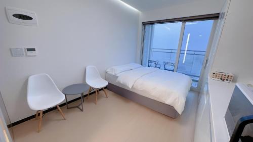 a bedroom with a bed and two chairs and a window at Shine Hotel Incheon Airport in Incheon