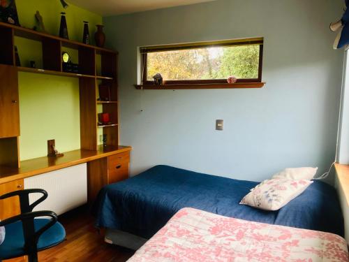 1 dormitorio con cama, escritorio y ventana en Casa Familiar con Vista al campo y al lago, en Puerto Varas