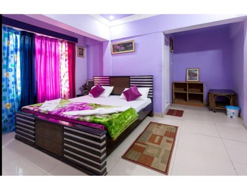 a bedroom with a large bed with purple walls at Hotel Nanda Lokpal, Ghangaria in Lokpāl