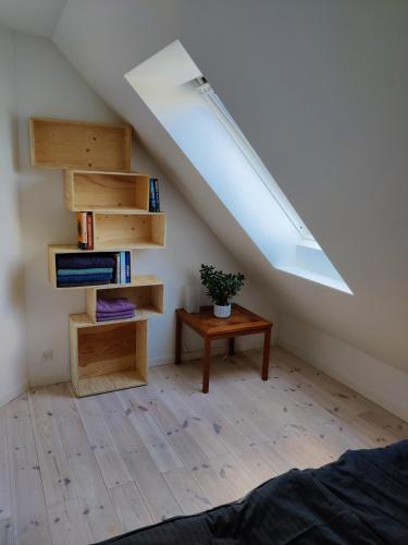een slaapkamer met een dakraam en een tafel met een plant bij Værelse med egen stue in Horsens