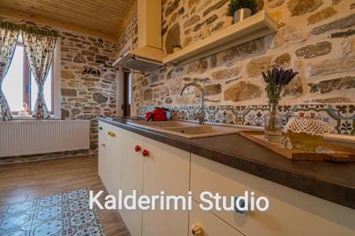 a large kitchen with a stone wall at Kalderimi Studio in Sotír