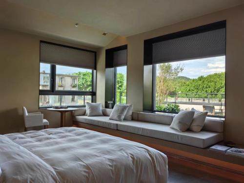 a bedroom with a large bed and large windows at Jiangnan House Chaozhou in Chaozhou