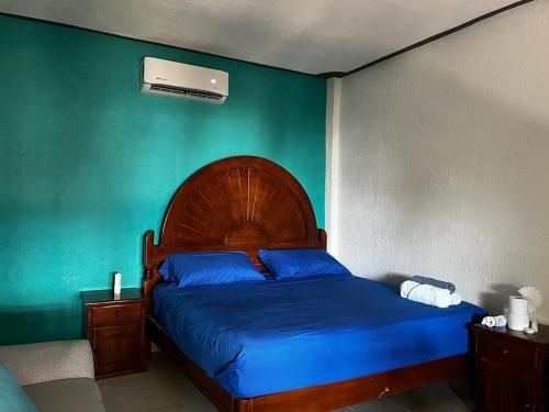 ein Schlafzimmer mit einem Bett mit blauer Bettwäsche und einer grünen Wand in der Unterkunft Casa del Sol in San Pedro Pochutla