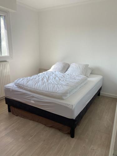 Una cama con sábanas blancas y almohadas. en BELLE VUE MER - Villers sur mer, en Villers-sur-Mer