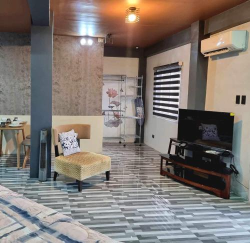 a living room with a tv and a couch and a chair at Rvenue apartelle in Lucban