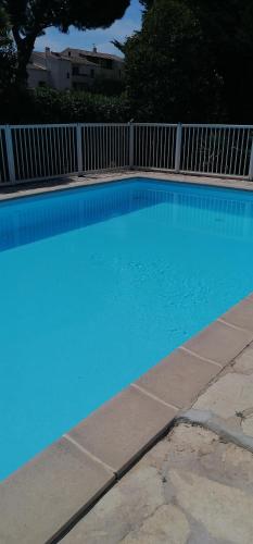 une grande piscine bleue à côté d'une clôture dans l'établissement T2 avec piscine 5 mn des plages et village, à Sanary-sur-Mer