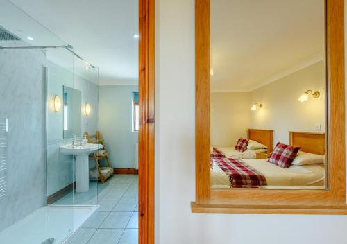 a bedroom with a bed and a bathroom with a mirror at Beudy Bach in Silian