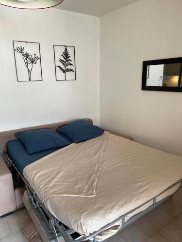 un lit dans une chambre avec deux tableaux au mur dans l'établissement T2 avec piscine 5 mn des plages et village, à Sanary-sur-Mer