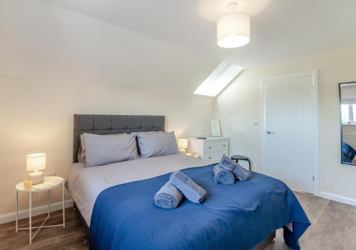 a bedroom with a large bed with blue sheets at Yr Hen Barlwr in Llanddyfnan