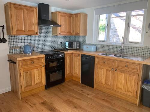 a kitchen with wooden cabinets and black appliances at Cottage with outstanding views in Velindre