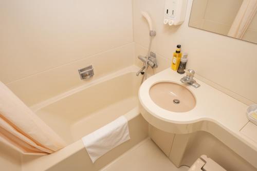 a white bathroom with a sink and a bath tub at Motobu Green Park and Golf Course in Motobu