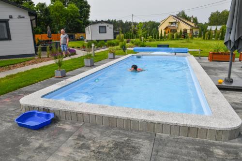 a person swimming in a large swimming pool at Barszczówka - domki, basen podgrzewany, prawdziwe jacuzzi, sauna infrared i inne atrakcje na Podlasiu in Kłyżówka