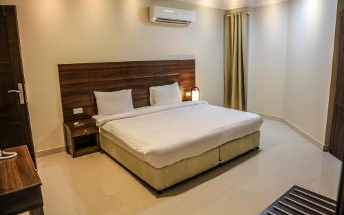 a bedroom with a large bed with a wooden headboard at Barka Hotel Apartment in Samhān