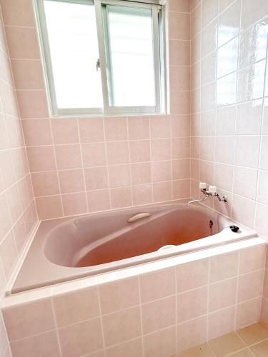 a bath tub in a bathroom with a window at SumiwaHouse in Yomitan