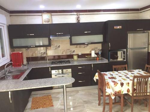a kitchen with black cabinets and a table and a kitchen with a tableablish at 2 minutes from Sheraton Oran. Come and relax here. in Oran