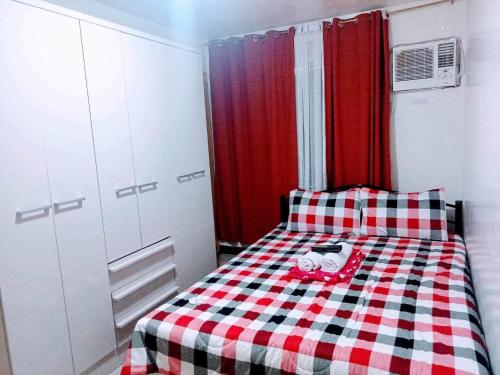 Un pequeño dormitorio con una cama a cuadros rojo y blanco en Koze De Casa Newly Renovated Staycation, en Imus