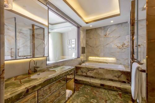 a bathroom with a tub and a sink and a mirror at Sheraton Huzhou Taihu Lake Hot Spring Resort & Spa in Huzhou