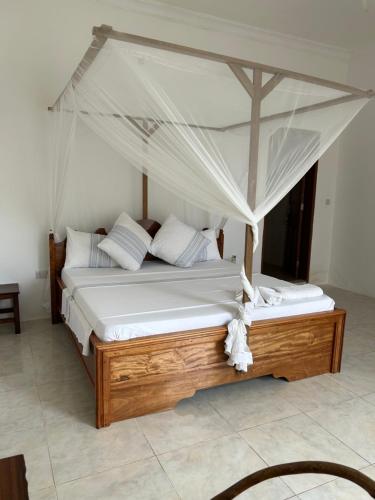 een groot bed met een baldakijn in een kamer bij Shamba Lodge in Nungwi