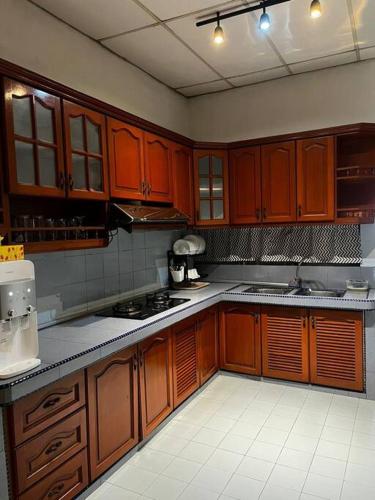 a kitchen with wooden cabinets and a stove top oven at Manjung Modern + Cozy Terrace Home in Lumut