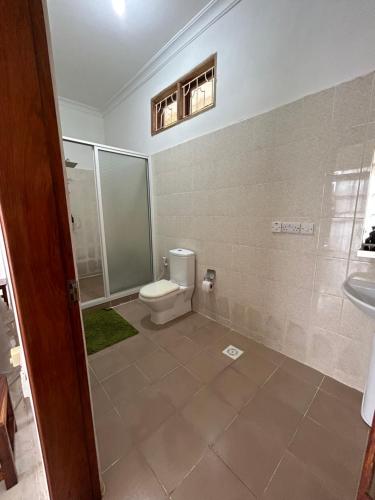 a bathroom with a toilet and a shower and a sink at Shamba Lodge in Nungwi