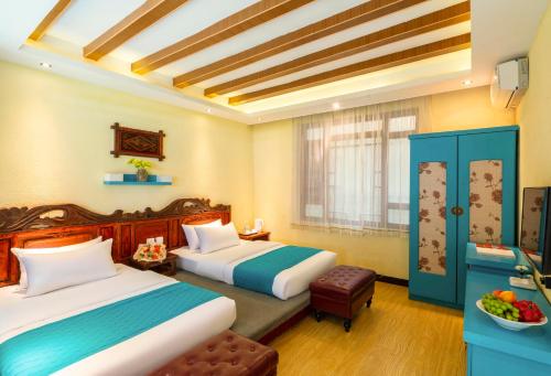 a hotel room with two beds and a bowl of fruit at Frida's Inn 丽江梦之旅观景客栈 in Lijiang