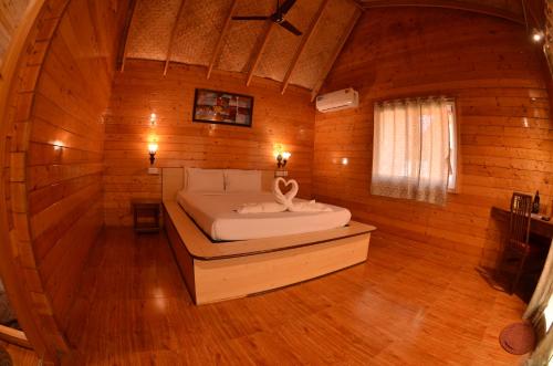 a bedroom with a bed in a wooden cabin at Alagoa Resort in Betalbatim