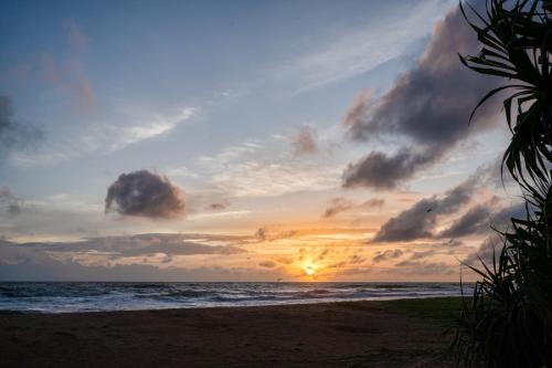 a sunset on a beach with the ocean at Kirana - A Santani Villa in Bentota