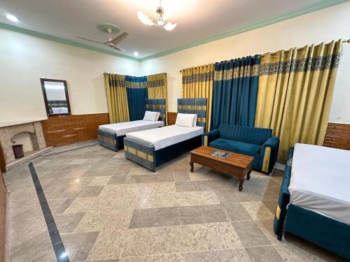 イスラマバードにあるDecent Lodge Guest House F-11のベッド2台とソファが備わるホテルルームです。