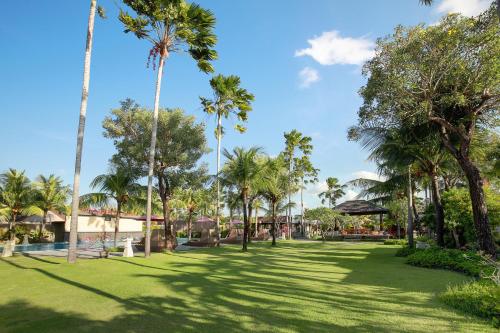 a park with palm trees on a sunny day at Lumbini Luxury Villas and Spa in Jimbaran