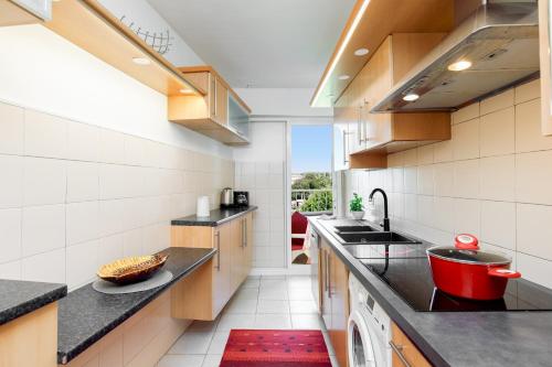 une cuisine avec des comptoirs noirs et un tapis rouge dans l'établissement Vue mer exceptionnelle sur plage du Midi en 1re ligne- 2 chambres, à Cannes