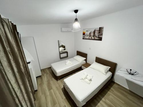 a bedroom with two beds and a table and a lamp at Full Moon Apartments in Ksamil