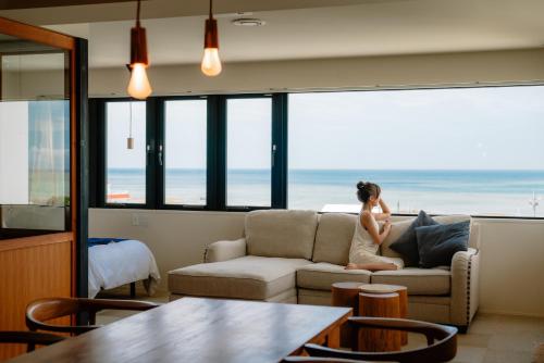 uma mulher sentada num sofá a olhar para o oceano em Blue Steak Wonder Yomitan em Yomitan