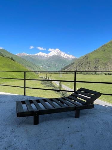 a bench sitting on the ground with mountains in the background at Gzaze in Stepantsminda