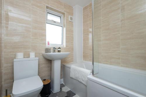 a bathroom with a toilet and a sink and a bath tub at Gorgeous Grange Fields Home - Free Parking, Self Check-in, High Speed Wi-fi, Excellent City Centre Access - Contractors Welcome in Leeds