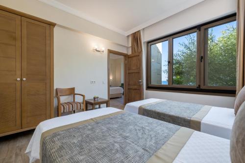 Gokceada TownにあるCinarli Kasriのベッド2台と窓が備わるホテルルームです。
