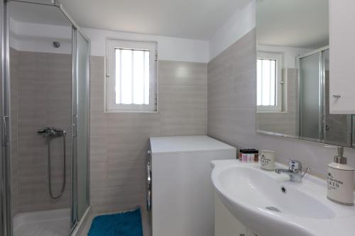 a white bathroom with a sink and a shower at Angelana Beach Villa in Faliraki