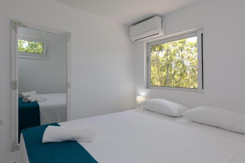 a white bedroom with a bed and a window at Angelana Beach Villa in Faliraki