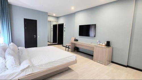 a bedroom with a bed and a desk and a tv at Resident Hotel Gogol in Almaty