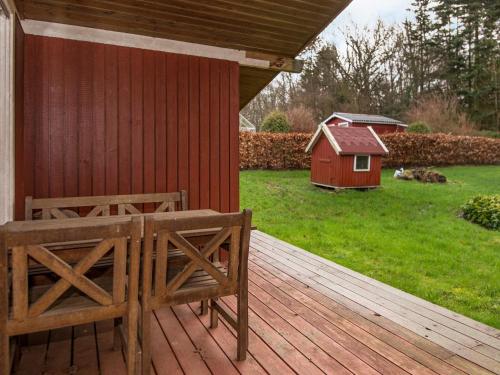 eine Holzterrasse mit einer Bank und einem Vogelhaus in der Unterkunft 6 person holiday home in F rvang in Fårvang