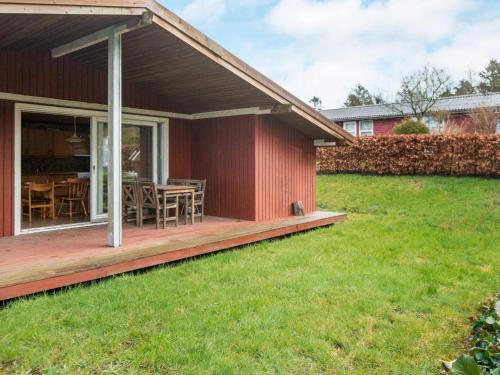 ein Haus mit einer Holzterrasse mit einem Rasenplatz in der Unterkunft 6 person holiday home in F rvang in Fårvang