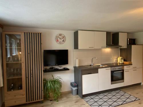 a kitchen with white cabinets and a sink and a tv at Appartment Kapferer in Gries im Sellrain